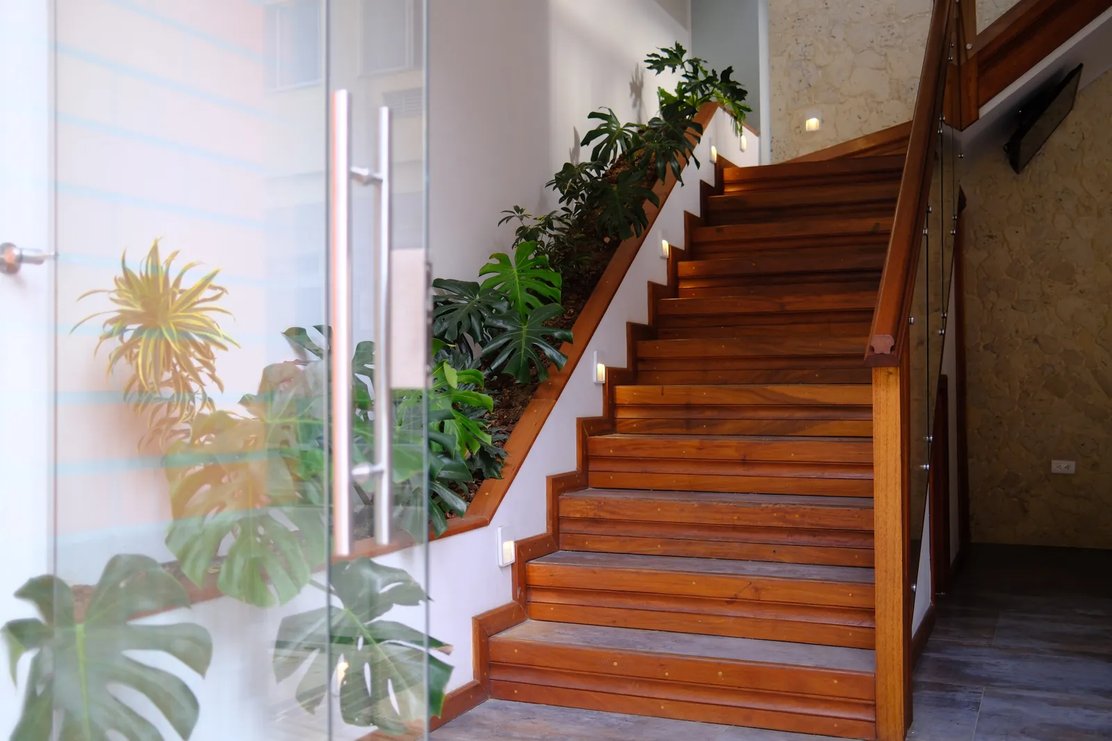 Escalera de madera del Hotel Los Samanes, rodeada de plantas